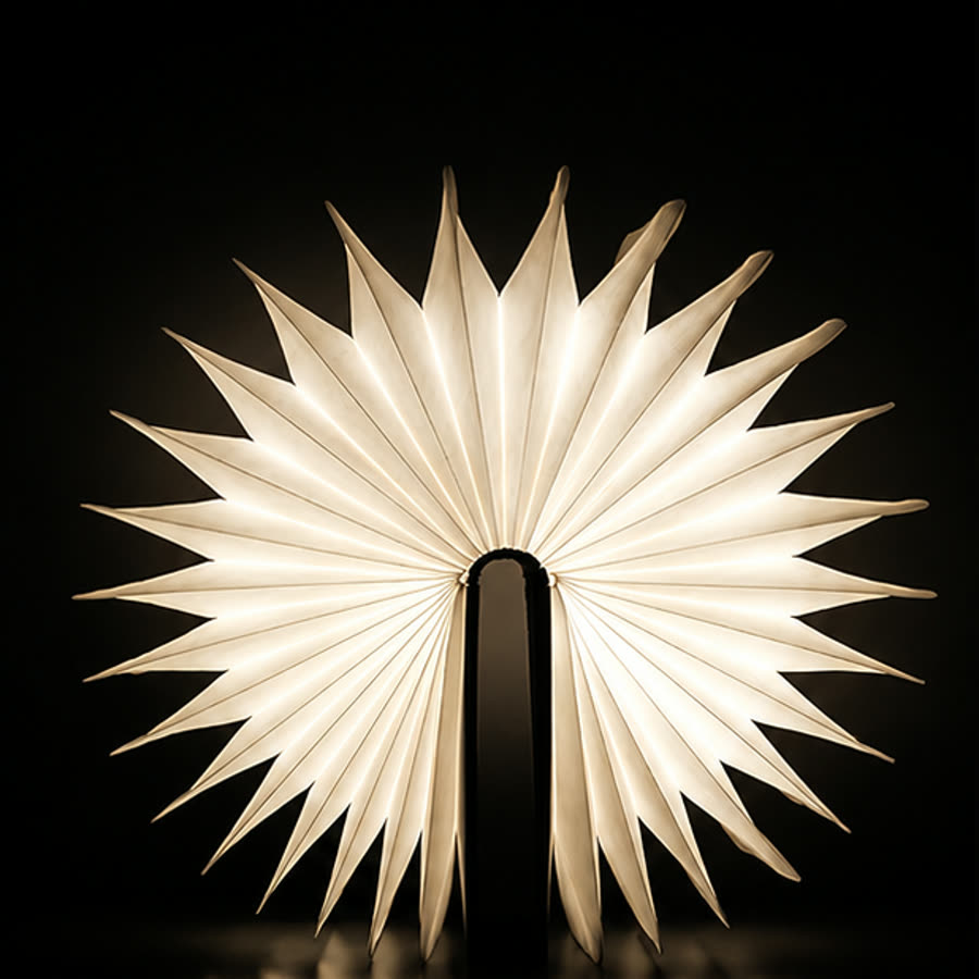 The Book Lamp open in a fan, lit warm against a dark room