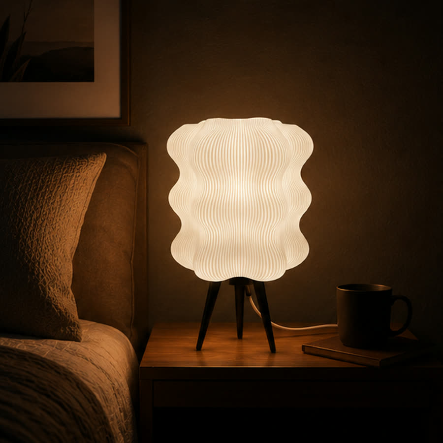 The Modern Ripple Table Lamp lit on a bedside table