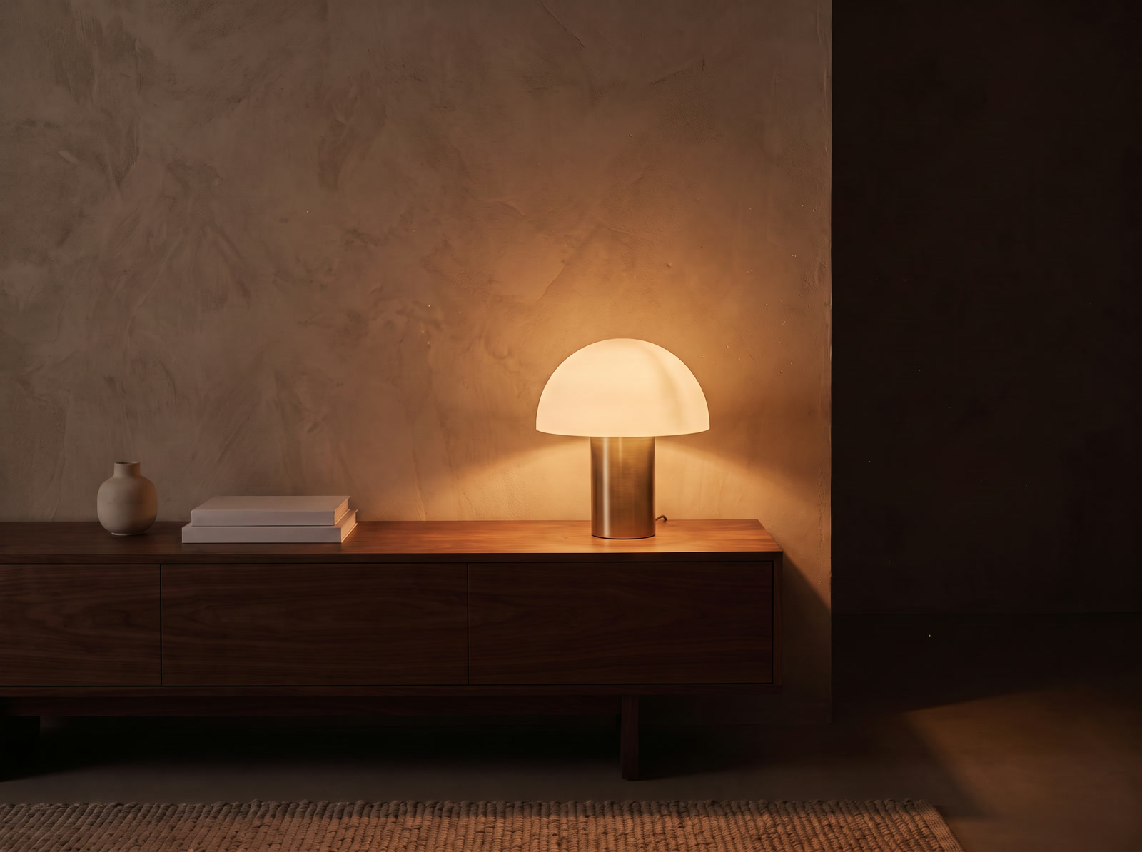 The same console at night lit only by a Kaelo lamp, a warm amber pool spreading up the plaster wall